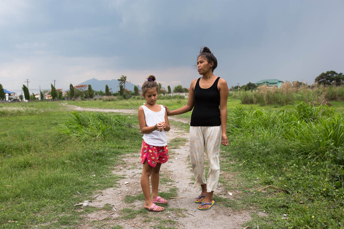 Nathalie and Blessimai - Nathalie, 32, and Blessimai, 9, on the field behind their house in Mabalacat, 15 km from Balibago. In a few months the construction of a shopping centre will begin here. In the background lies Mount Arayat (1026m), an extinct volcano. Mabalacat near Angeles City, Philippines, May 2015. - Copyright © © S. Borcard - N. Metraux - Mabalacat City - Central Luzon - Philippines - <A href="https://maps.google.com/?ll=15.228963,120.605763&z=16" target="_blank">(Map Nathalie and Blessimai)</A>