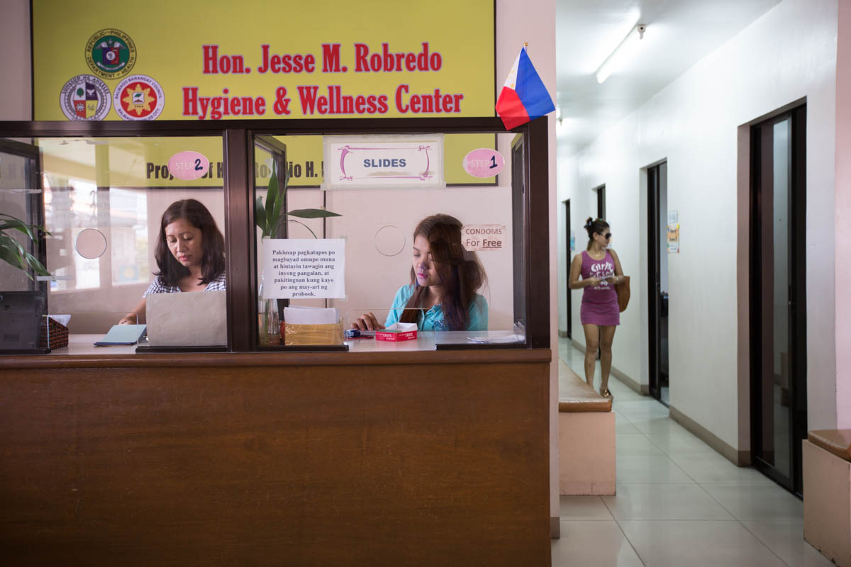 Hygiene Center - Teresa Lyn, 24, and Charmaine, 38, at the front desk of the Balibago Social Hygiene Clinic. All women working in Fields must be checked for STI’s once a week. The result will then be printed on an ID tag that all women must wear while working. The clinic opened its doors in July 2011.  Angeles City, Philippines, May 2015. - Copyright © © S. Borcard - N. Metraux - Angeles - Central Luzon - Philippines - <A href="https://maps.google.com/?ll=15.166258,120.590958&z=16" target="_blank">(Map Hygiene Center)</A>