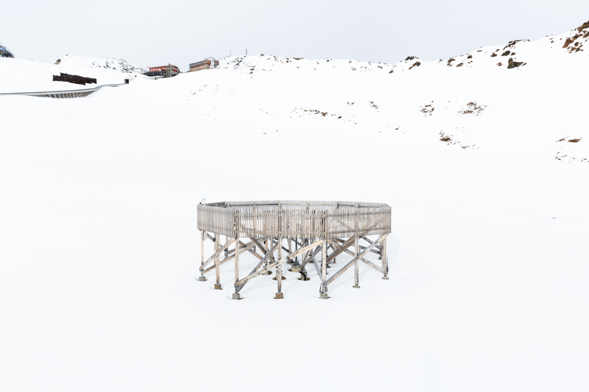 Die Holzstruktur bricht den Wind und hilft den Forschern, die genaue Menge von Schneeniederschlag zu messen. Im Hintergrund steht die Endstation der Parsennbahn. Versuchsfeld Weissfluhjoch, Davos, November 2017.